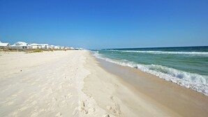 Ein Strand mit blauem Himmel, sandigem Ufer und Strandhäusern.