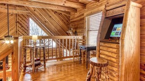 A wooden cabin interior with a wooden ceiling, a staircase, a table with chairs, a mounted deer head, and a mounted television. - ER45 - Tin Pan Alley - Great location. Just across from swimming pool! (Pigeon Forge)