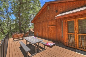 Eine Holzhütte mit einer Veranda, einem Picknicktisch und Bänken.