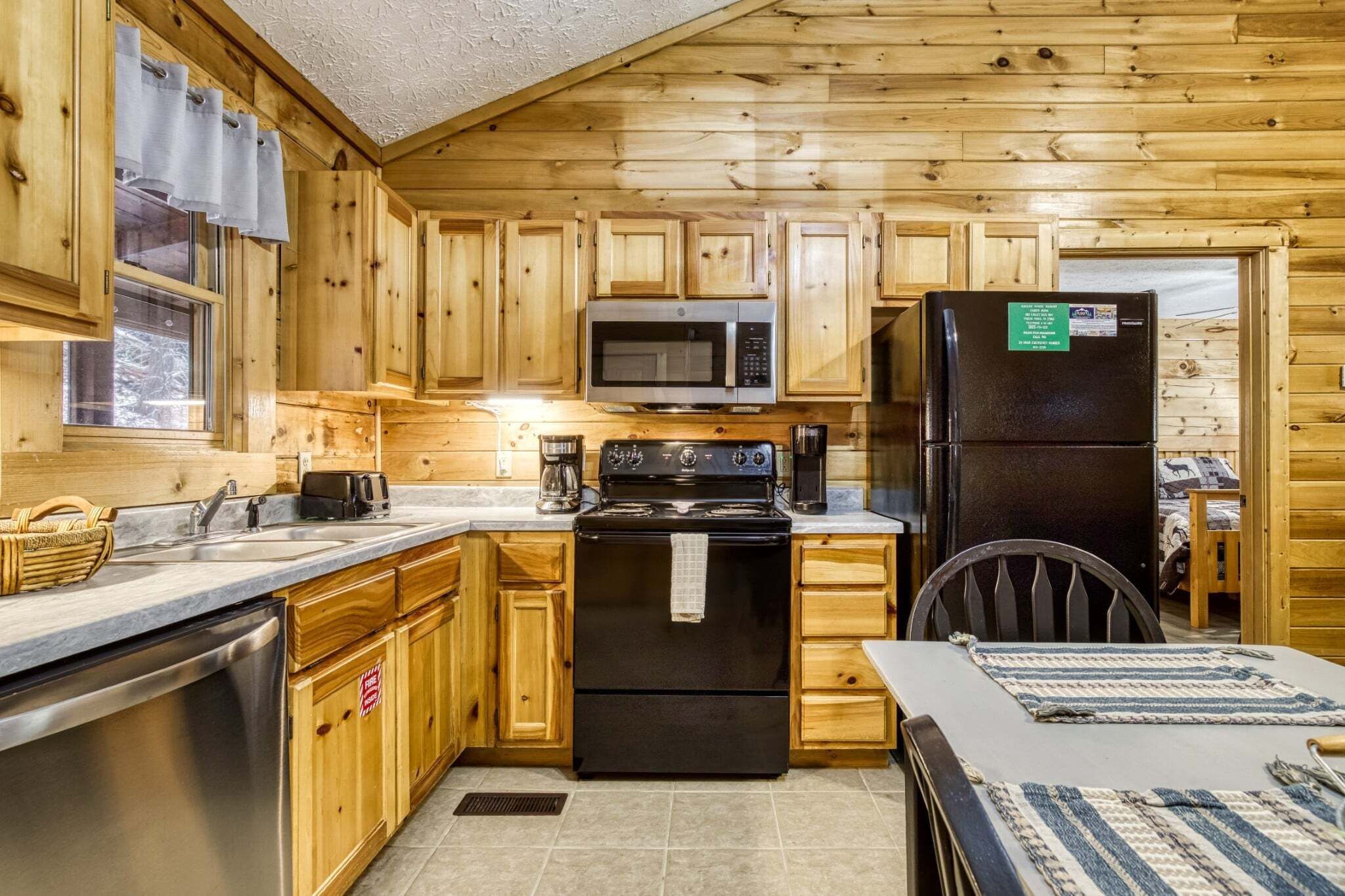 Una cucina in stile baita in legno, con microonde, fornello, frigorifero e pensili in legno.