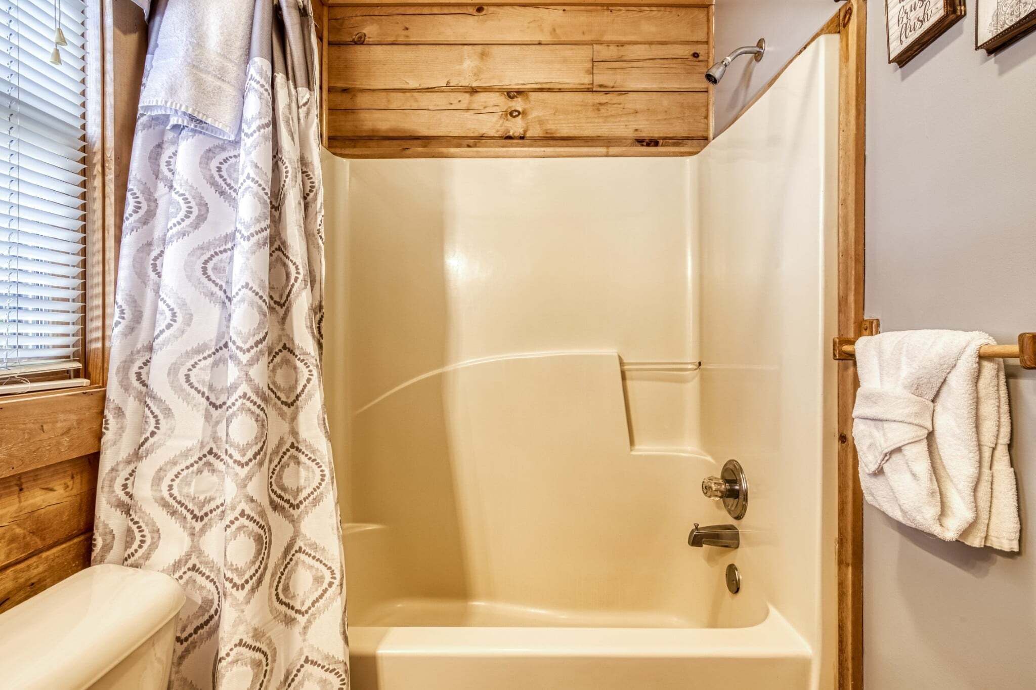 Une douche avec un plafond en bois, une baignoire blanche et un porte-serviettes.