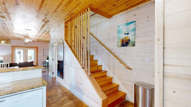 Un intérieur en bois comprenant un escalier, un coin cuisine et un espace repas.