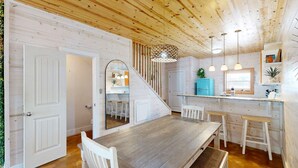 Un intérieur rustique en bois comprenant un coin repas, une cuisine et un escalier.