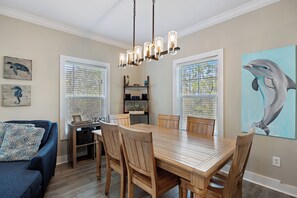 Un coin repas avec une table et des chaises en bois, un lustre et des œuvres d’art accrochées aux murs.
