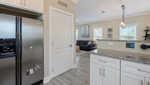 Una cocina moderna con electrodomésticos de acero inoxidable, armarios blancos y encimera de granito.