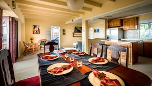 A dining area with a wooden table set for four, a kitchen with modern appliances, and a living area with a sofa and artwork. - Villa 1: Your Perfect Island Family Retreat (Gros Islet)