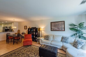 Un salon comprenant un canapé, un pouf et un coin repas avec des chaises et une table.