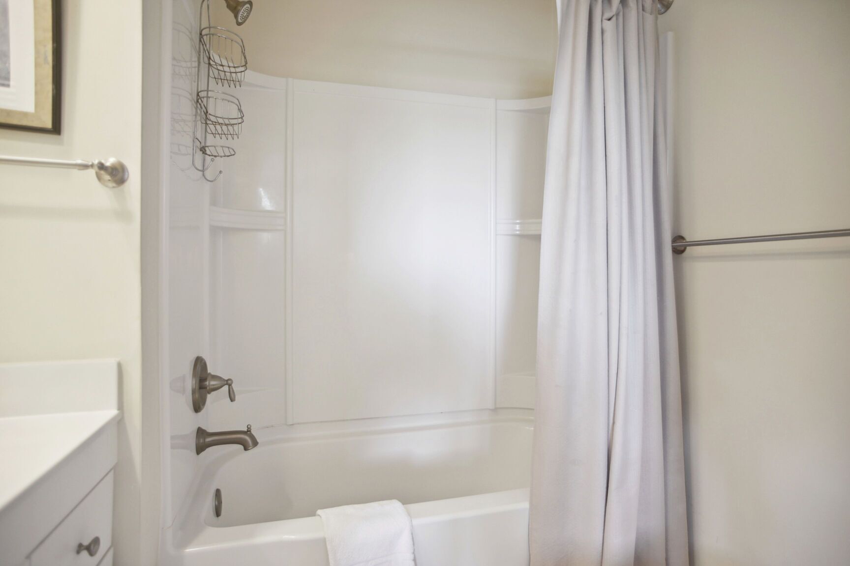 A bathroom with a bathtub, a shower curtain, and a towel rack.