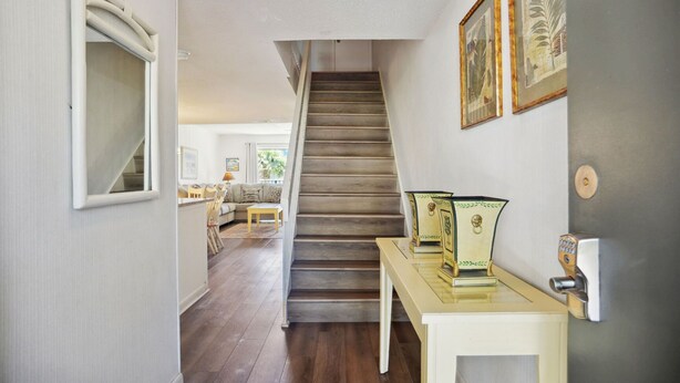 Eine Treppe führt zu einem Wohnbereich mit einer Couch und einem Couchtisch, einem kleinen Tisch mit Dekoration und gerahmten Kunstwerken an der Wand.
