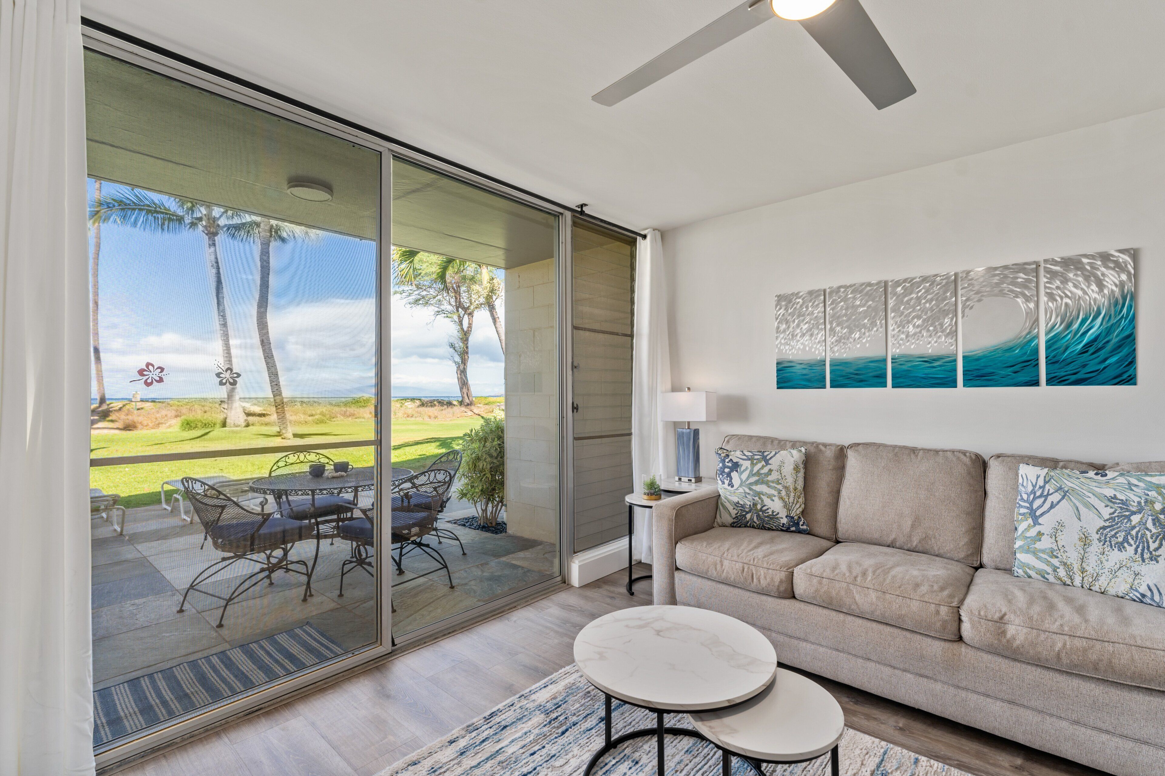 Una sala moderna con un ventanal corredera que da a un patio con mobiliario exterior.