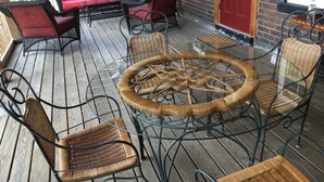 A covered outdoor seating area with wicker chairs and a glass-top table, a red sofa, and a brick wall in the background. - NEWPORT INN #1 - NO CLEANING FEES!! FREE PARKING!! WALK TO GAMES AND CONCERTS!! (Newport)