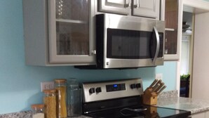 Una cocina con encimeras de granito, electrodomésticos de acero inoxidable y armarios blancos.