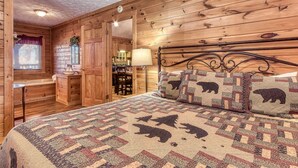 Une chambre confortable, aménagée dans le style d’un chalet, avec des murs en bois, un lit recouvert d’une couverture matelassée, un banc en bois, une petite table et une fenêtre avec des stores.