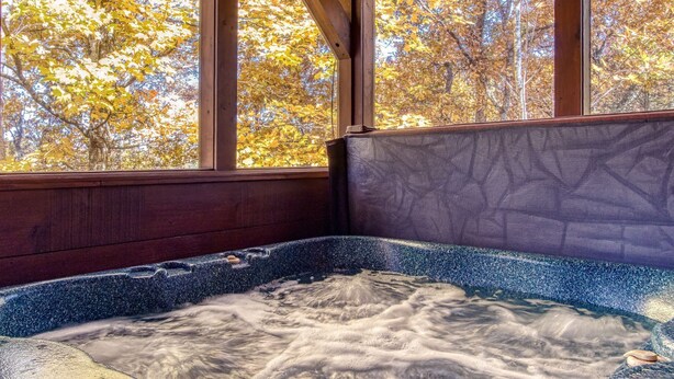 Un bain à remous avec vue sur les arbres aux couleurs automnales, grâce à de grandes fenêtres.