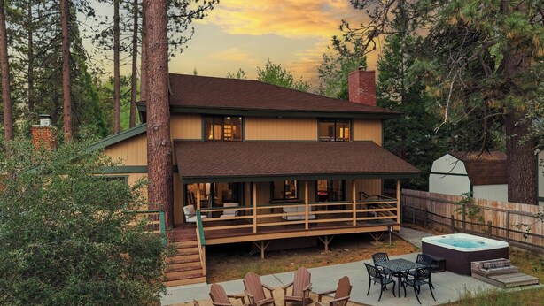 A two-story house with a covered patio, outdoor seating, and a hot tub. - Luxury! Pool Table! Hot Tub! Pet Friendly! Covered Deck! 4 Master Suites! Log Features! (Big Bear City)