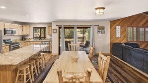 A modern kitchen with wooden cabinets, a central island, and bar stools. - Luxury! Pool Table! Hot Tub! Pet Friendly! Covered Deck! 4 Master Suites! Log Features! (Big Bear City)