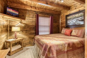 A wooden cabin bedroom with a bed, a nightstand, a lamp, and a painting on the wall. - ER47 - Moody Blue - Great location. Close to all the action! (Pigeon Forge)