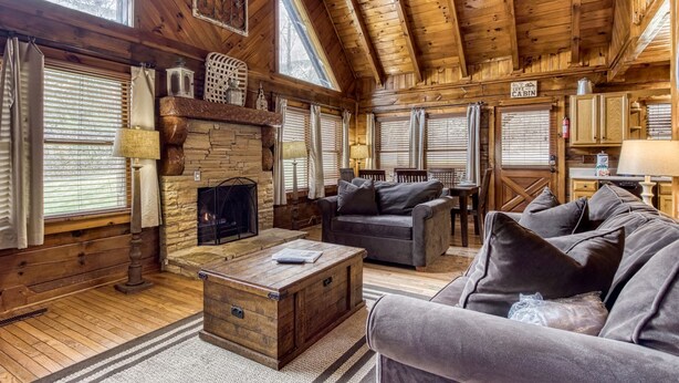 A cozy cabin interior with a stone fireplace, wooden floors, and a rustic aesthetic.