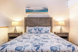 Relax in a serene bedroom with a large bed, two nightstands, and a framed beach scene above.