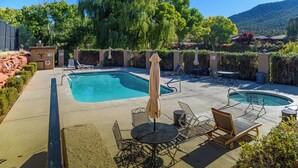 A pool area with two pools, lounge chairs, and umbrellas.