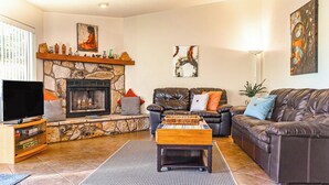 A living room with a stone fireplace, leather sofas, a coffee table, and artwork on the walls.