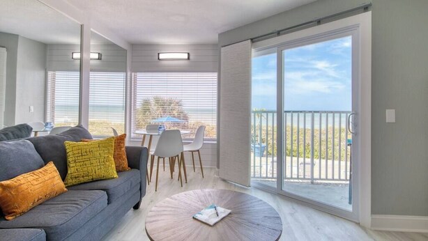 Una sala moderna con sofá, sillas, una mesita de centro y un balcón con vistas.