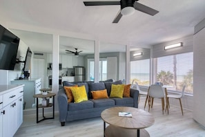 A modern living room with a sofa, coffee table, and dining area.