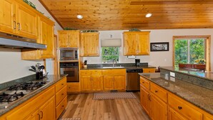A kitchen with wooden cabinets, a stainless steel stove, and a window with a view of greenery.