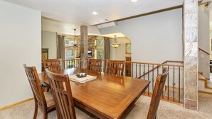 Ein Esszimmer mit Holztisch und -stühlen, einem Steinkamin und einer Treppe mit Geländer.