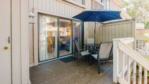Katettu terassi, jossa on pöytä ja tuoleja, sininen aurinkovarjo sekä liukuovet, jotka johtavat sisätiloihin.