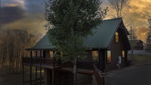 A cabin with a wooden exterior, a balcony, and a stone foundation.