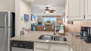 A kitchen with granite countertops, stainless steel appliances, and a view to the living area. - Beach Walks, Sunset Views & Coastal Bliss – Islander 417 (Destin)