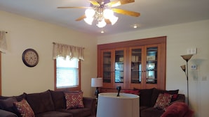 A living room with a brown sofa, a coffee table, a lamp, and a bookshelf. - Rural Retreat yet close to the sites. Cedar point*Jet Express* African Safari (Port Clinton)