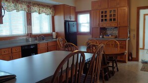 A kitchen with wooden cabinets, a central island, and a dining table with chairs. - Rural Retreat yet close to the sites. Cedar point*Jet Express* African Safari (Port Clinton)