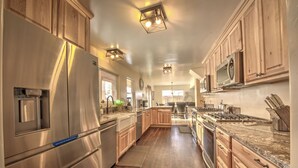 A modern kitchen with stainless steel appliances, wooden cabinets, and a granite countertop.