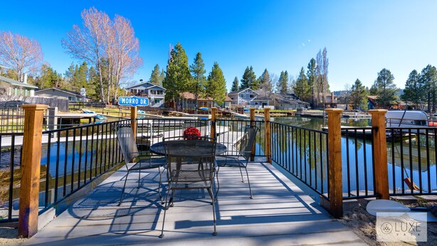 A waterfront patio with a table and chairs, a sign reading "MORRO DRY," and a wooden fence.