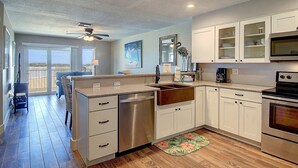 A modern kitchen with white cabinets, a dishwasher, an oven, and a ceiling fan. - Poolside, spacious and bright! Community boardwalk access to beach (Port Aransas)