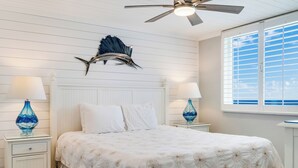 A bedroom with a bed, two nightstands with lamps, a ceiling fan, and a window with blinds. - 🌊Islander #509 – Where the Sand is the Softest & the Views Are Endless🏖️✨ (Destin)