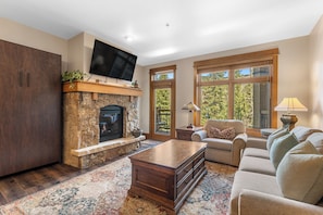 A living room with a stone fireplace, a flat-screen TV, a sofa, and a coffee table.