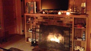 Una sala de estar acogedora con una chimenea, un televisor montado encima y un cartel en la pared que dice "SIMPLIFY".