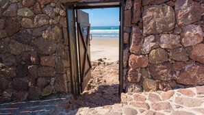 A stone wall with a wooden door leading to a beach. - Oceanfront Villa Amor (Villas Corona)