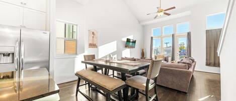 Una cocina amplia con comedor, ventilador de techo y ventanas grandes.