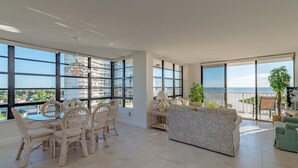Zona saló àmplia amb grans finestres que ofereixen vistes a la ciutat i al mar. Hi ha un menjador i un sofà amb vistes.