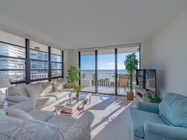 A spacious living room with a large window, a sofa, a coffee table, and a TV.