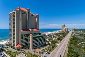 Een hoog hotel met een rood dak, meerdere verdiepingen en uitzicht op het strand en de oceaan.
