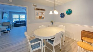 Un espace repas avec une table ronde, des chaises blanches et un lustre.