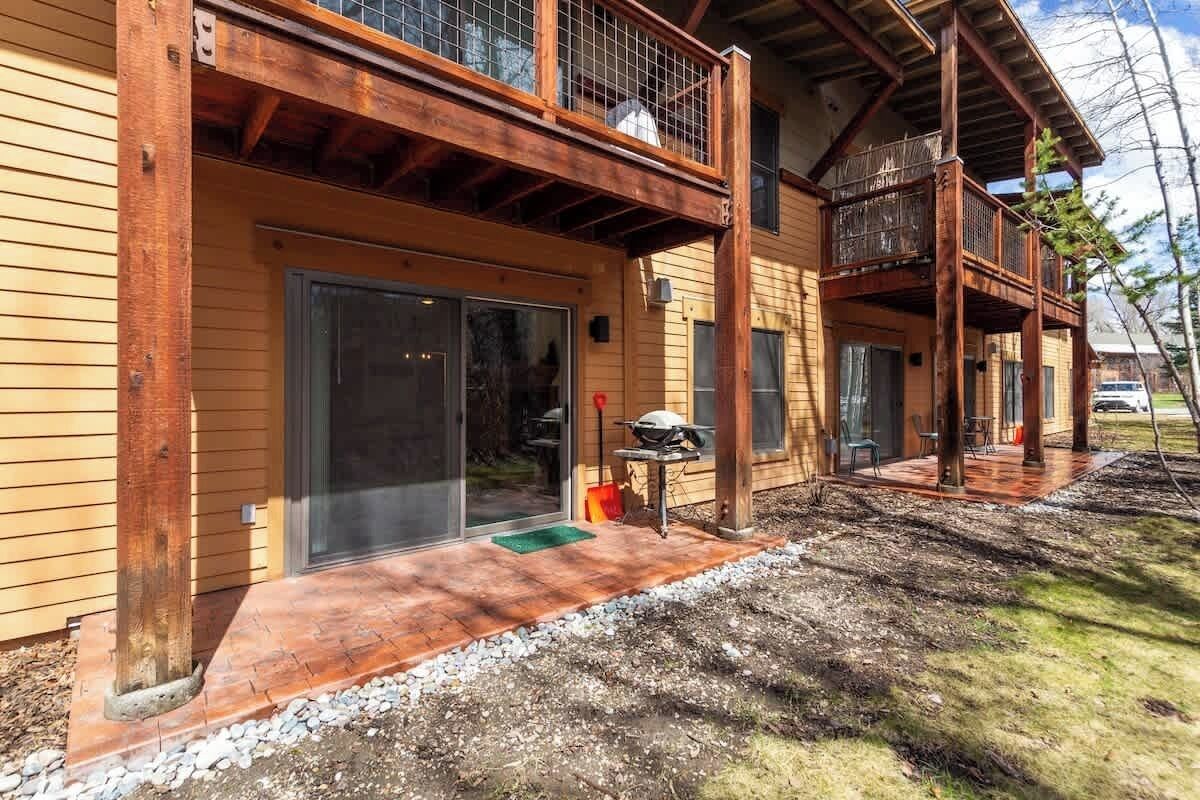 A wooden cabin with a covered porch, a sliding glass door, and outdoor seating.