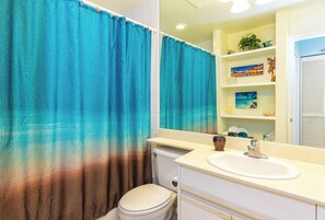 A bathroom with a white toilet, a white sink, and a blue shower curtain.
