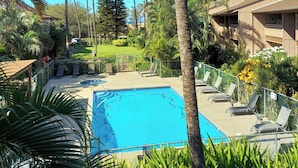 A pool area with lounge chairs and palm trees. - Partial Ocean View from private lanai, Queen Bed.....fully furnished condo (Kihei)