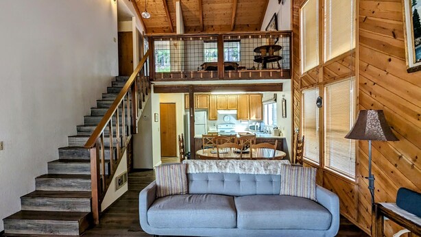 Ein gemütliches Blockhaus-Interieur mit einer Treppe zu einem Schlafzimmer auf dem Dachboden, einem Essbereich und einer Küche.